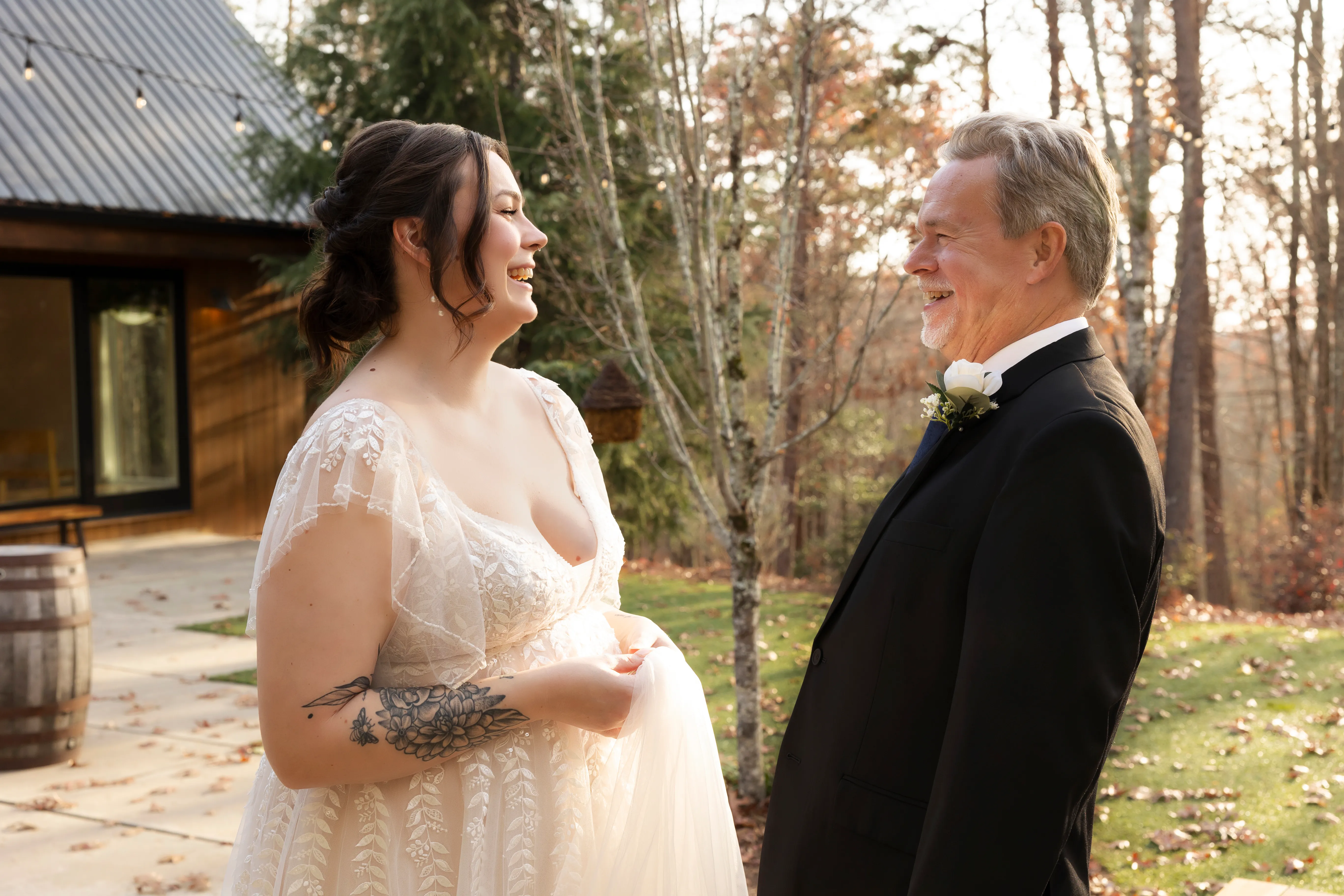 Bride and her father sharing a laugh during their first look at an outdoor barn venue