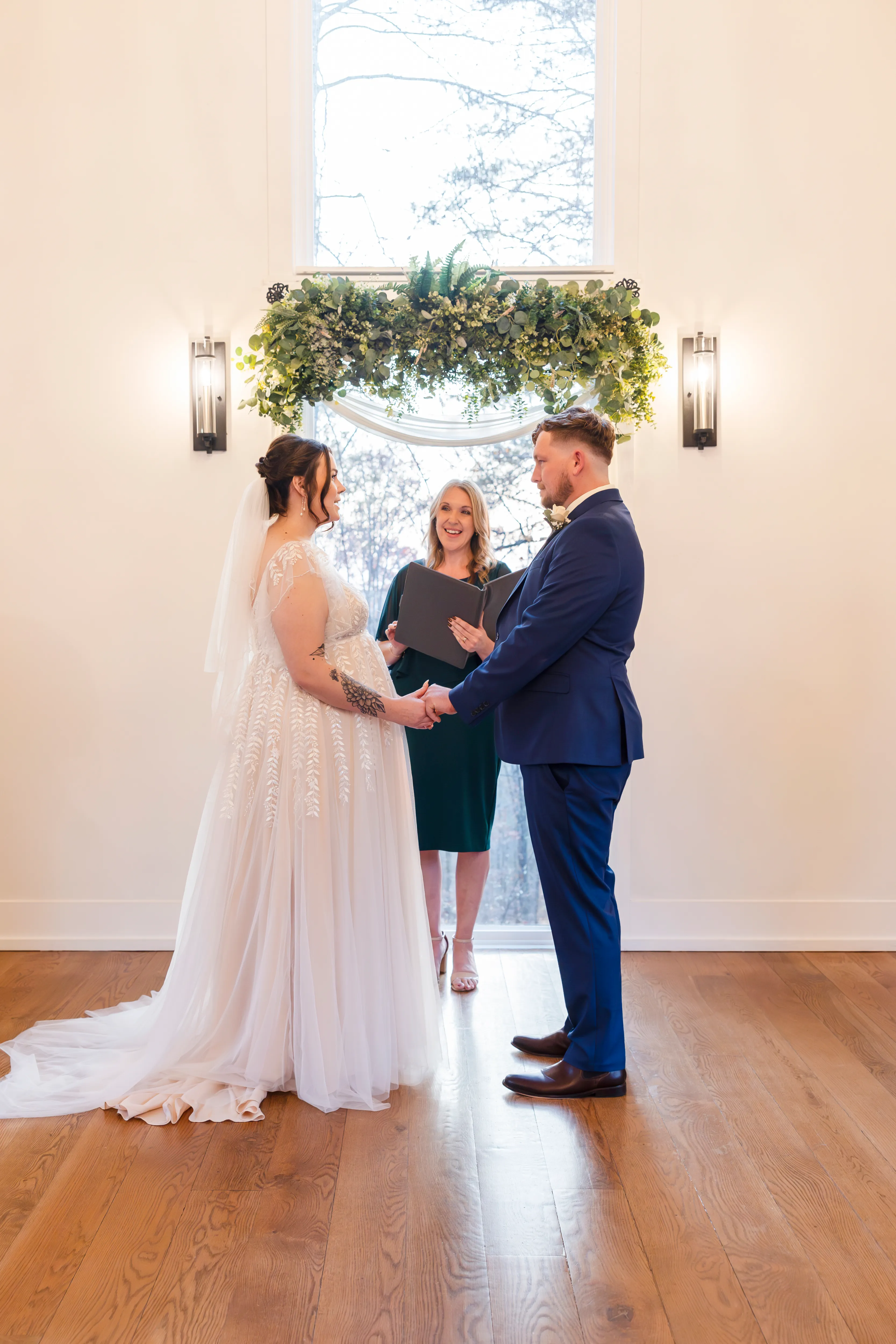 Bride and groom exchanging vows at the altar of Juliette Chapel under a greenery arch