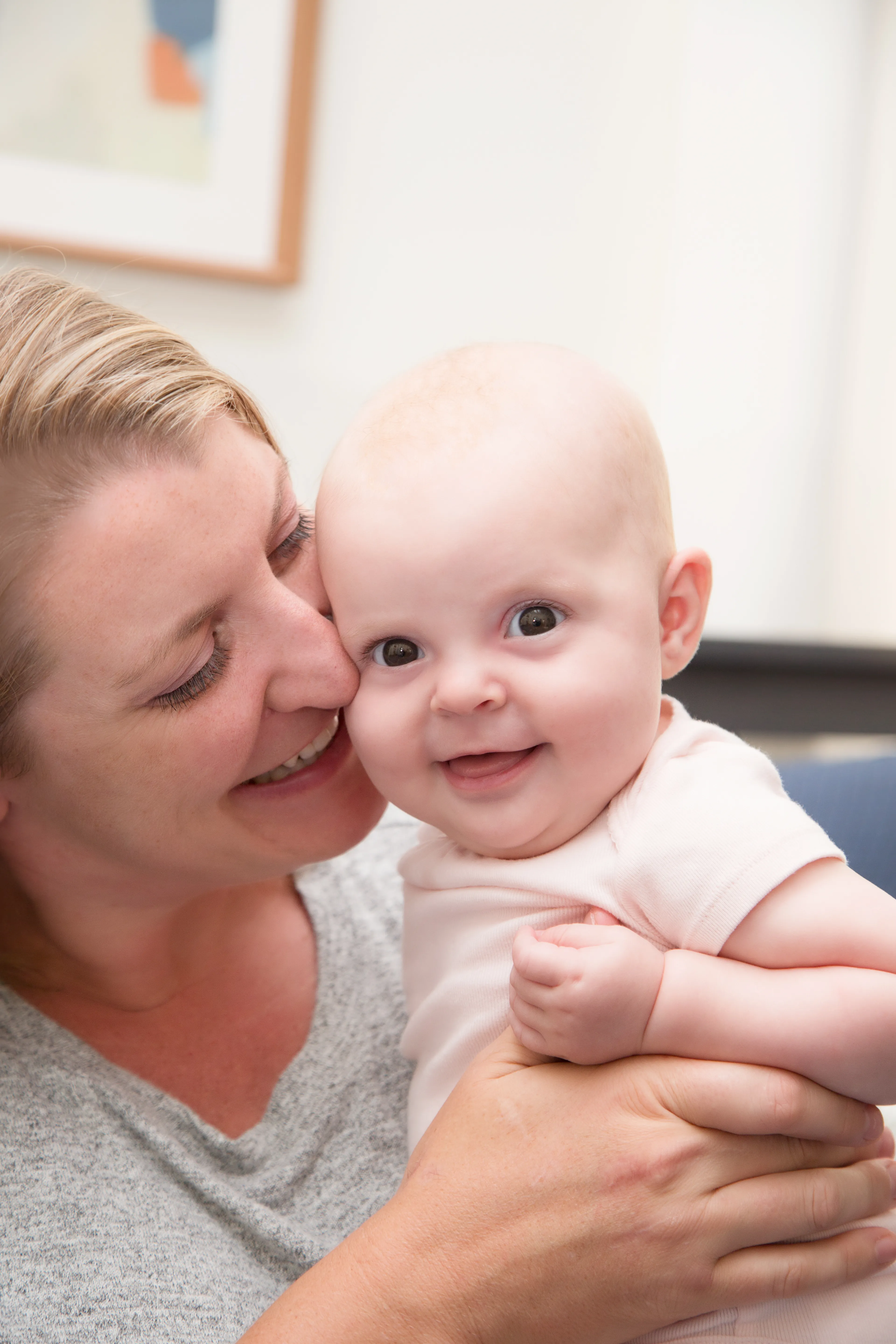 Mother holding newborn cheek to cheek in an intimate in-home portrait